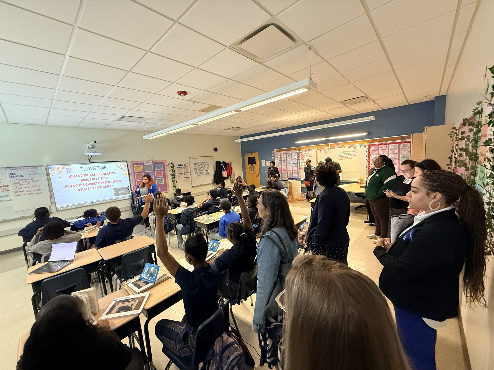 School leaders observing a New Orleans classroom as students raise their hands